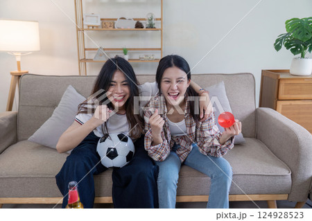 Cheerful lesbian couple enjoying football game at home living room candid photo cozy atmosphere joyful moment Cheerful lesbian couple enjoying football game at home living room candid photo cozy atmosphere joyful moment 124928523