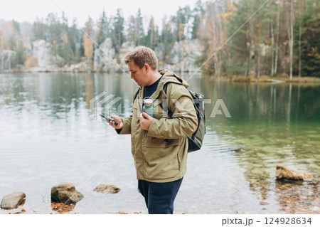 Travel backpacker standing with phone near the majestic lake. Travel, adventure. Concept of an active lifestyle. High quality photo 124928634