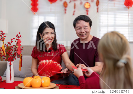 Celebrating chinese new year with family grandparents and granddaughter gather for festivities in a cozy home environment Celebrating chinese new year with family grandparents and granddaughter gather for festivities in a cozy home environment 124928745