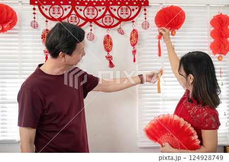 Elderly chinese couple celebrating chinese new year together at home festive decorations joyful atmosphere Elderly chinese couple celebrating chinese new year together at home festive decorations joyful atmosphere 124928749