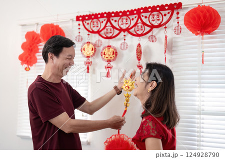 Elderly couple celebrates chinese new year at home festive decorations joyful atmosphere intimate moment Elderly couple celebrates chinese new year at home festive decorations joyful atmosphere intimate moment 124928790