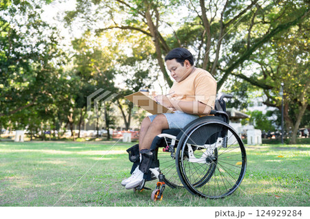 Young Man in Wheelchair Enjoying Outdoor Activities in a Sunny Park Setting with Greenery and Trees Young Man in Wheelchair Enjoying Outdoor Activities in a Sunny Park Setting with Greenery and Trees 124929284