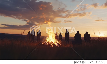 Group silhouettes around a glowing bonfire at golden sunset, celebrating the summer solstice with warmth, freedom, and nostalgic energy under open skies. 124931489
