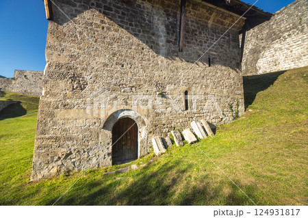 Walled City of Jajce, medieval fortress in Jajce town in Bosnia and Herzegovina, Europe. Exterior view of a weathered stone building with a wooden door, showing its historical architecture. 124931817