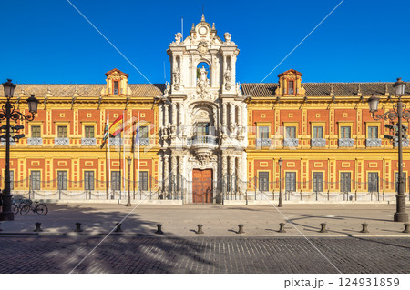 The Palace of San Telmo in Seville town, capital of Andalusia in Spain. Grand palace facade with ornate details, under a bright blue sky. Flags fly proudly. 124931859