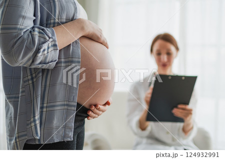 Pregnant woman hands touching big belly in doctor office. Female doctor examining pregnant woman. Gynecologist doctor consulting patient about pregnancy in hospital. Visit to doctor medical checkup Pregnant woman hands touching big belly in doctor office. Female doctor examining pregnant woman. Gynecologist doctor consulting patient about pregnancy in hospital. Visit to doctor medical checkup 124932991
