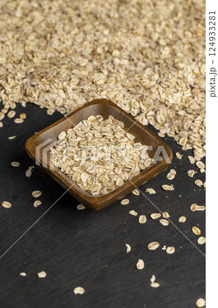 oat flakes poured into a square-shaped wooden bowl, oatmeal for quick cooking of porridge , close up, side view oat flakes poured into a square-shaped wooden bowl, oatmeal for quick cooking of porridge , close up, side view 124933281