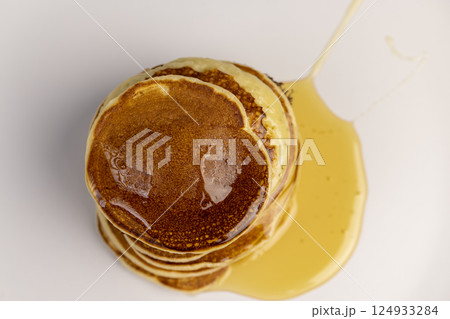 drizzled with honey a large number of delicious pancakes stacked together on a white bowl, a tower of small milk pancakes drizzled with honey a large number of delicious pancakes stacked together on a white bowl, a tower of small milk pancakes 124933284