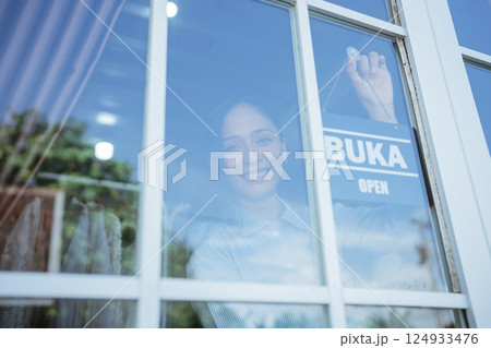 Smiling Woman Inside Caf with Open Sign in Window Smiling Woman Inside Caf with Open Sign in Window 124933476