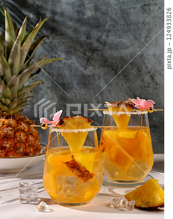 Refreshing summer diet drink recipe,Cold homemade cocktail or lemonade with pineapple, orange, ice on sunny kitchen table,Detox diet and summer party concept.restaurant menu,selective approach 124933826