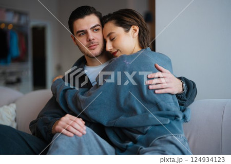 Couple embracing on a couch in a cozy indoor setting during the evening Couple embracing on a couch in a cozy indoor setting during the evening 124934123