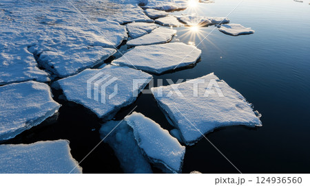 Melting icebergs with sunlight reflecting on water create serene scene 124936560