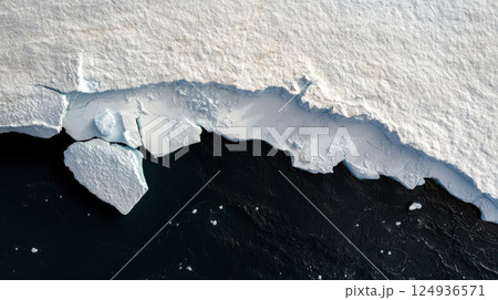 Melting iceberg with large sections calving into dark ocean water Melting iceberg with large sections calving into dark ocean water 124936571