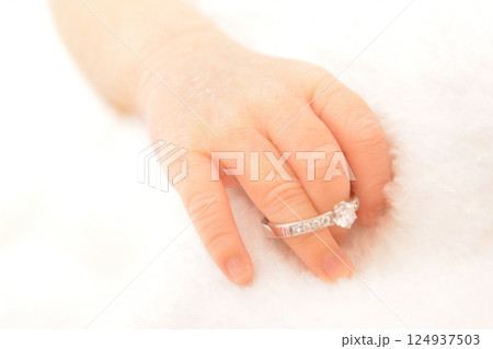 赤ちゃんの指にお母さんの婚約指輪をつけて記念撮影 124937503