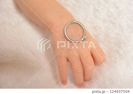 赤ちゃんの指にお母さんの婚約指輪をつけて記念撮影 赤ちゃんの指にお母さんの婚約指輪をつけて記念撮影 124937504