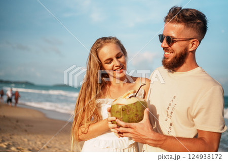 Smiling Couple Enjoying Fresh Coconut Drinks on a Beautiful Beach Smiling Couple Enjoying Fresh Coconut Drinks on a Beautiful Beach 124938172