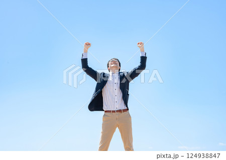 青空の下でガッツポーズをする男性 124938847