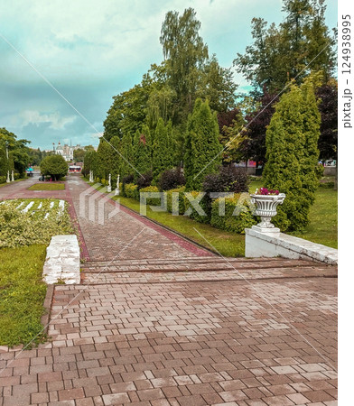 A beautiful view of a city park with statues and vases along a paved walkway 124938995