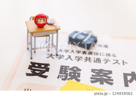 大学入試共通テストの受験案内、学校机とダルマのミニチュア 124939562
