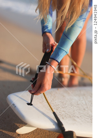 A Surfer Preparing for an Exciting Surfing Session on the Beautiful Beach with Her Surfboard 124941948