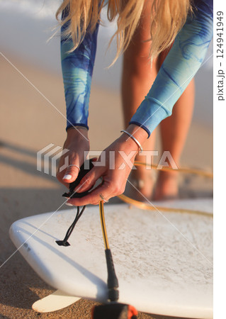A Surfer Preparing for an Exciting Surfing Session on the Beautiful Beach with Her Surfboard 124941949