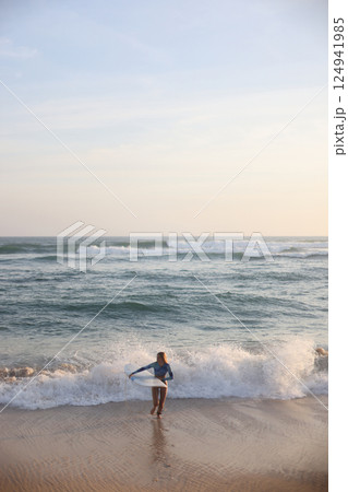 A person joyfully enjoying the waves at a beautiful sunset beach in the evening 124941985