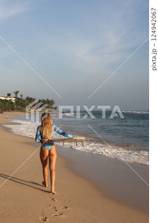 A Surfer Eagerly Prepared to Ride the Cresting Waves on a Stunningly Beautiful Beachside 124942067