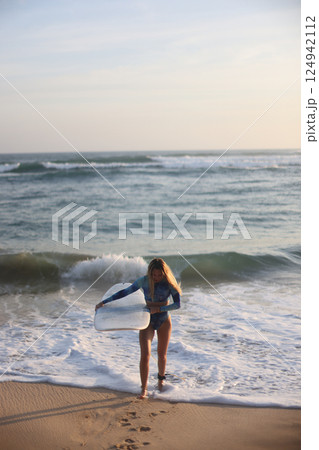 Enjoy thrilling surfing adventures as the sun sets beautifully over the serene beach 124942112