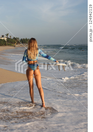 A Surfer Eagerly Prepared to Ride the Cresting Waves on a Stunningly Beautiful Beachside 124942119