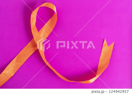 Orange ribbon on a bright pink background representing awareness and support efforts. 124942957