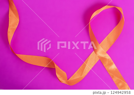 Orange awareness ribbon on a vibrant pink background for health support concept. 124942958