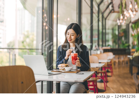 Happy asian woman healthy eating breakfast sandwich at cafe sitting near window indoors on day Happy asian woman healthy eating breakfast sandwich at cafe sitting near window indoors on day 124943236