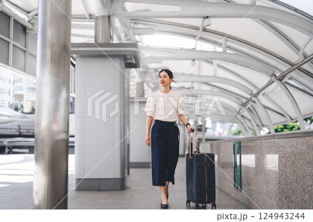 Adult business asian woman walking with luggage for work and travel at station platform on day 124943244