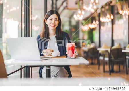 Happy asian woman healthy eating breakfast sandwich at cafe sitting near window indoors on day Happy asian woman healthy eating breakfast sandwich at cafe sitting near window indoors on day 124943262