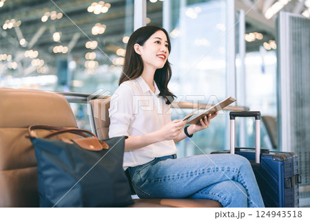 Adult passenger business asian woman sitting with luggage for global trip at airport terminal Adult passenger business asian woman sitting with luggage for global trip at airport terminal 124943518