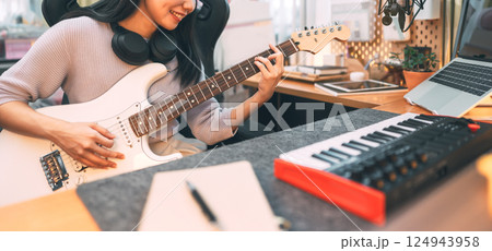 Young asian woman composer playing guitar music with digital technology at home studio 124943958