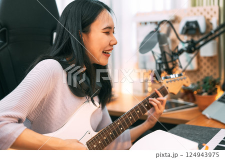 Young asian woman composer playing guitar music with digital technology at home studio Young asian woman composer playing guitar music with digital technology at home studio 124943975