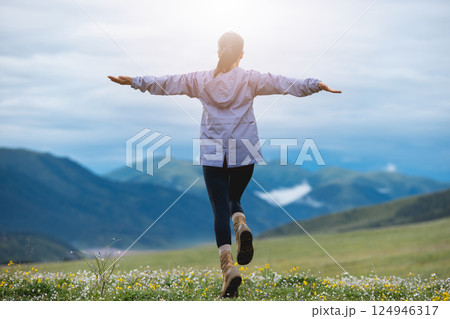 Woman hiker on beautiful flowering grassland mountain top Woman hiker on beautiful flowering grassland mountain top 124946317