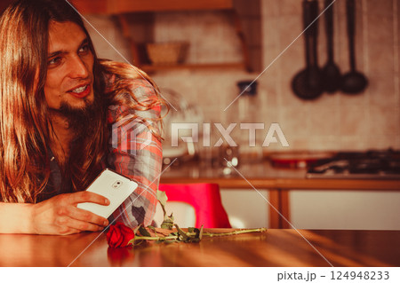 Worried man with rose and mobile phone. 124948233
