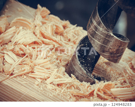 Metal machine drilling in wooden board 124948283