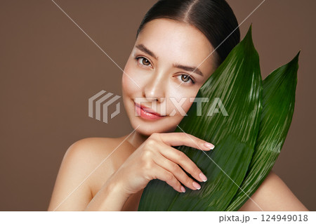 Close up girl face with green exotic leaves Close up girl face with green exotic leaves 124949018