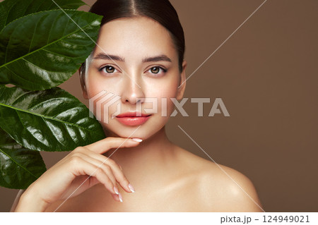 Close up woman face with green exotic leaf Close up woman face with green exotic leaf 124949021