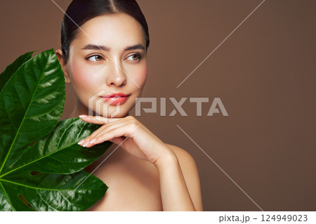 Close up woman face with green exotic leaf Close up woman face with green exotic leaf 124949023