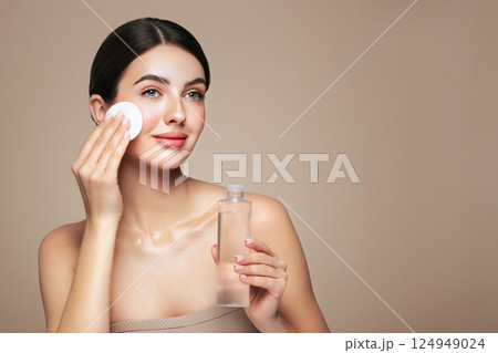 Young woman cleansing face with cosmetic milk Young woman cleansing face with cosmetic milk 124949024