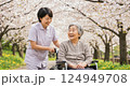 桜並木の下で介護師と散歩中の車椅子の老人女性 124949708