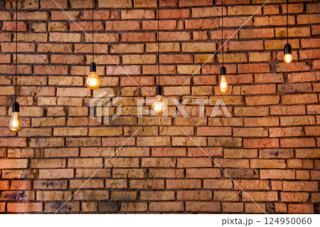 Old electric incandescent lamps with tungsten filament. Against the backdrop of a brick wall. Texture of old stone background. Old electric incandescent lamps with tungsten filament. Against the backdrop of a brick wall. Texture of old stone background. 124950060