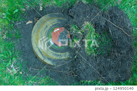 Green anti tank mine on the grass in the ground. 124950140