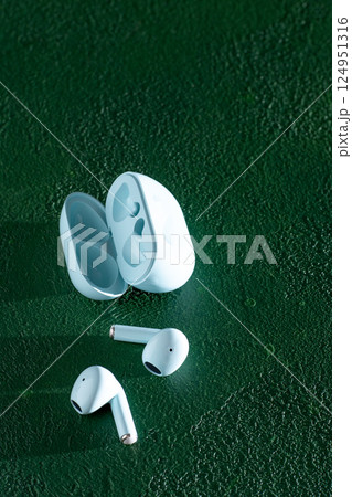 Wireless headphones on green background. Wireless, headphone in charging box. Wireless headphones on green background. Wireless, headphone in charging box. 124951316