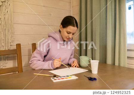 Young artist creating an artwork at a cozy table in a bright indoor space during the day Young artist creating an artwork at a cozy table in a bright indoor space during the day 124952325