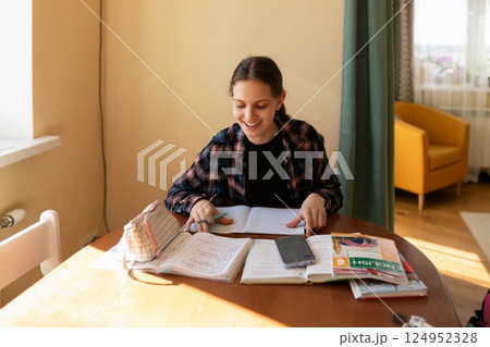 Student studying in a cozy room with books, notebook, and a phone on a sunny afternoon 124952328